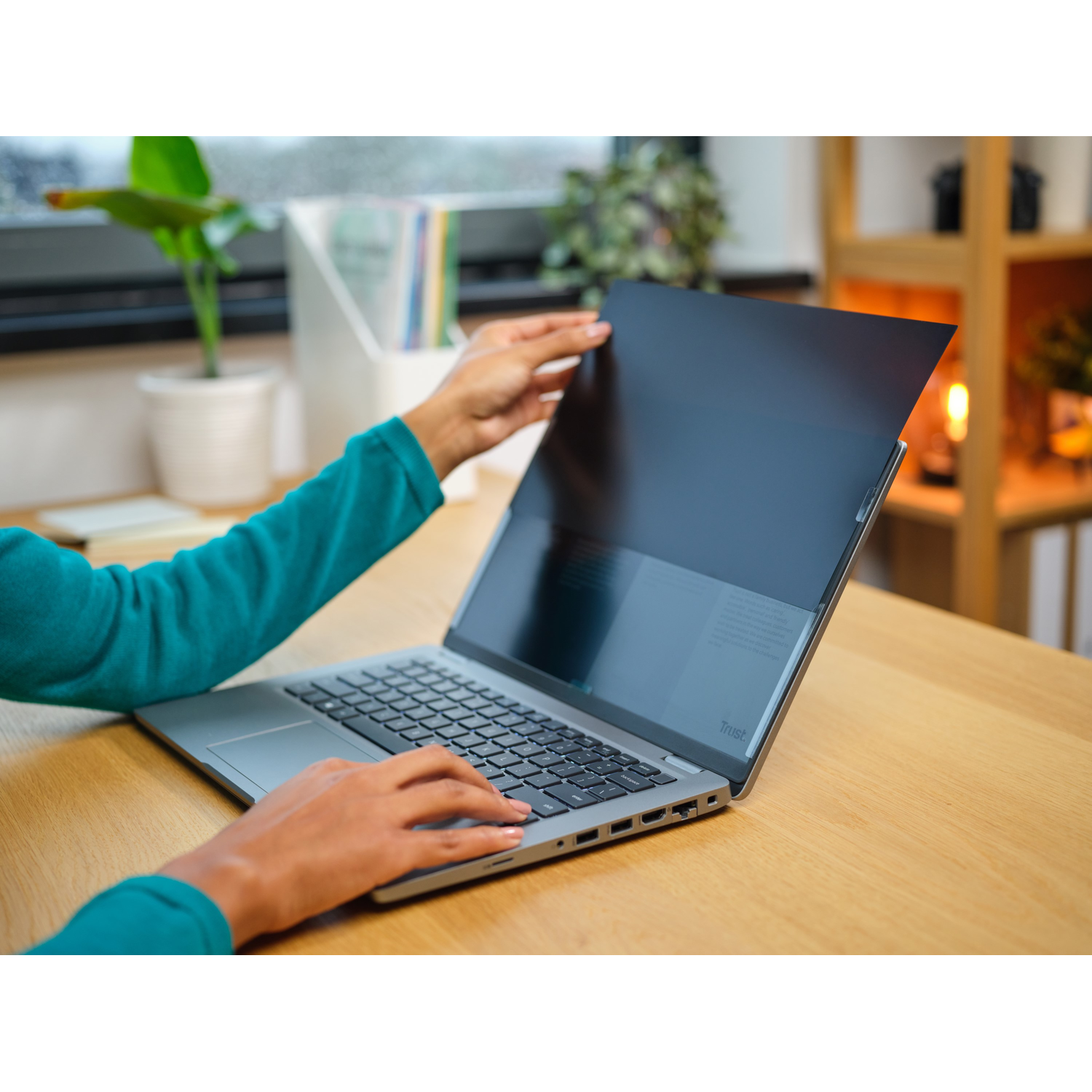 Handen die een laptop vasthouden met een privacyfilter geïnstalleerd.