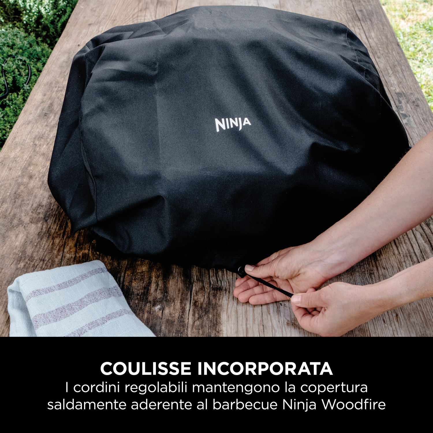 Una copertura per grill Ninja nera su un tavolo di legno con un asciugamano.