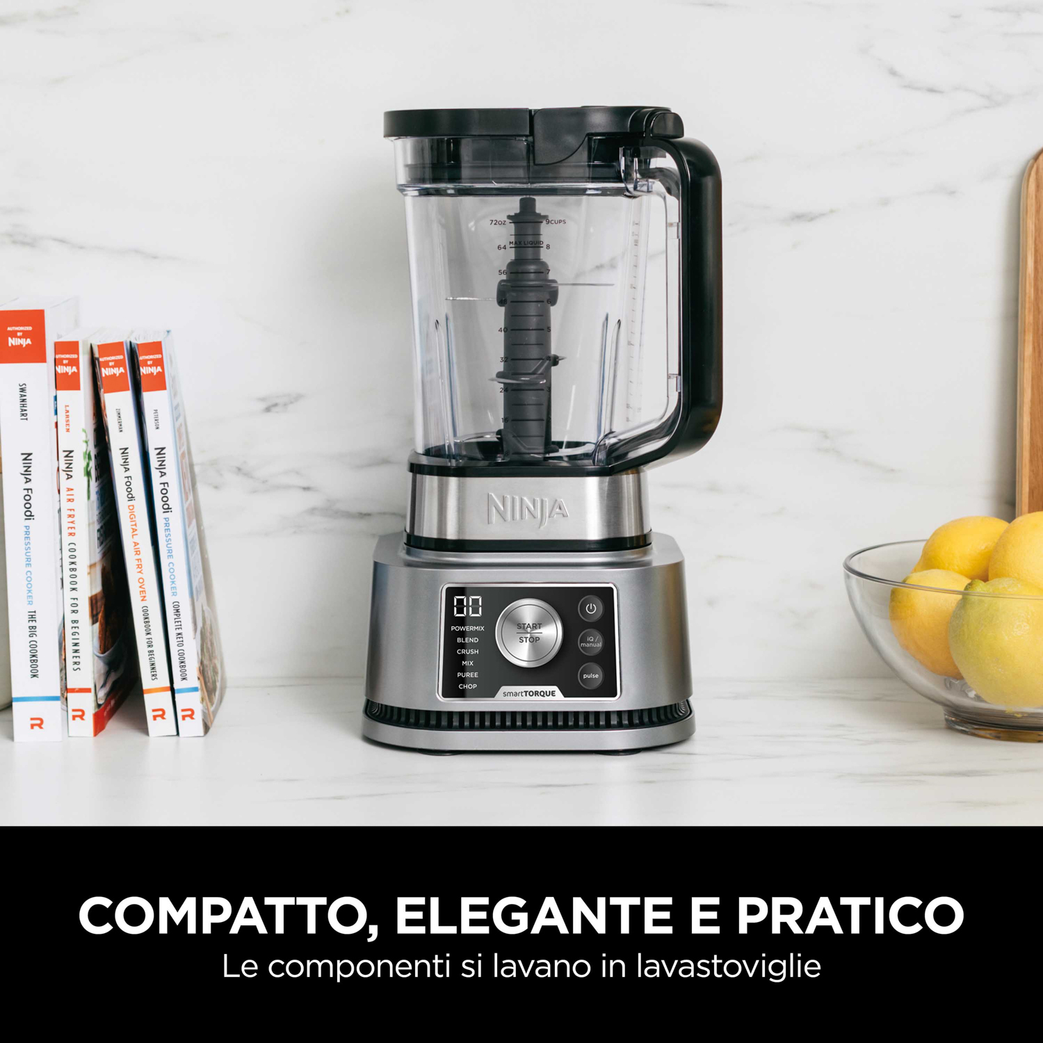 Frullatore Ninja su un bancone con libri di cucina e una ciotola di limoni nelle vicinanze.