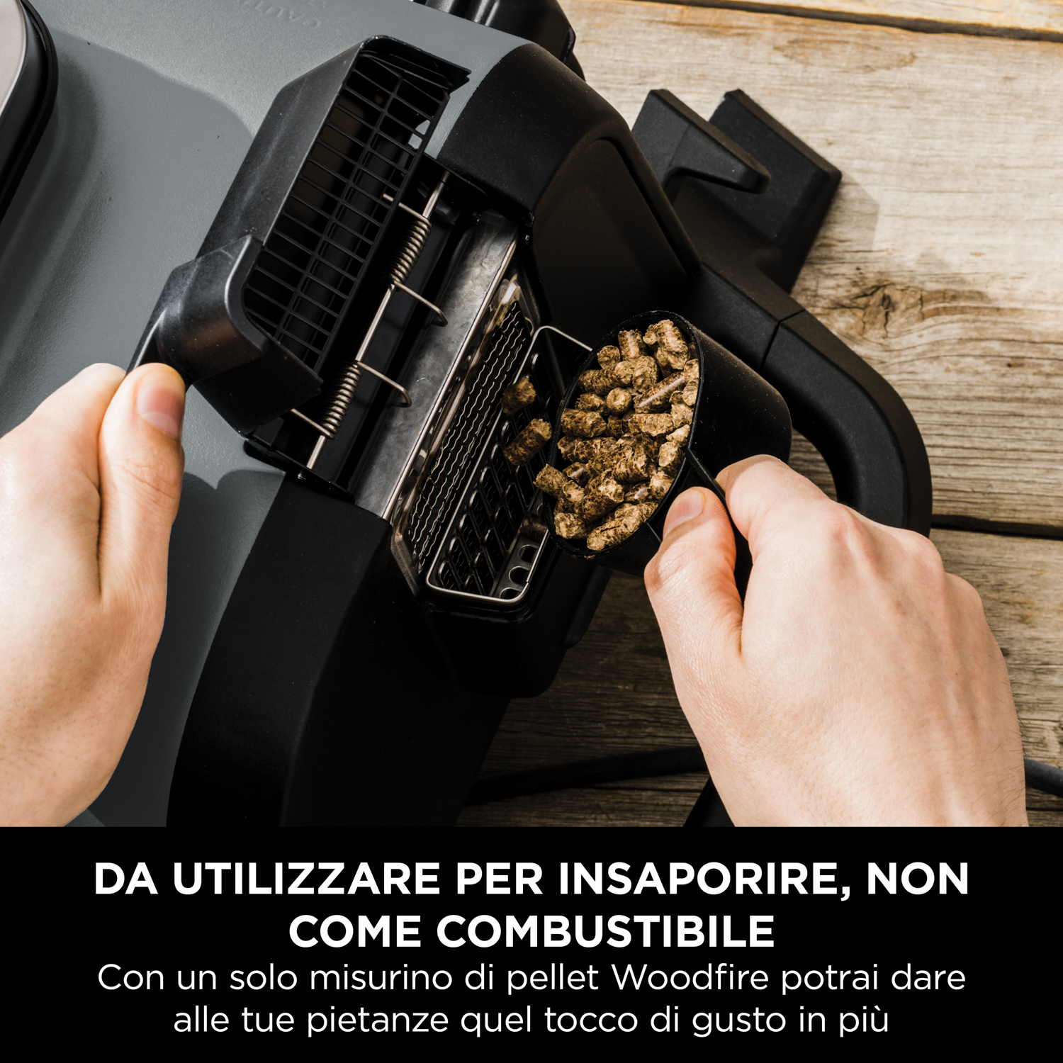 Persona aggiunge pellet di legno a un affumicatore. Mani con paletta, affumicatore nero con testo italiano.