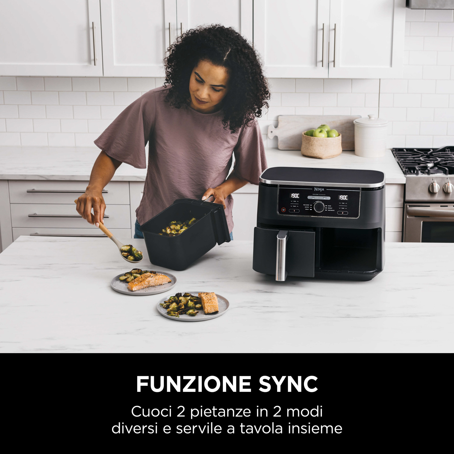 Una donna che usa una friggitrice ad aria Ninja, con verdure e salmone cotti, su un ripiano della cucina.