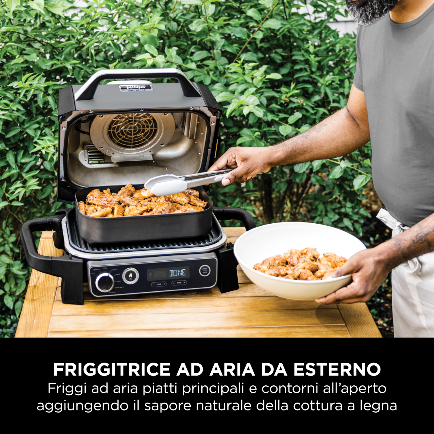 Una persona che griglia cibo su una griglia esterna, con pinze e una ciotola di cibo cotto.
