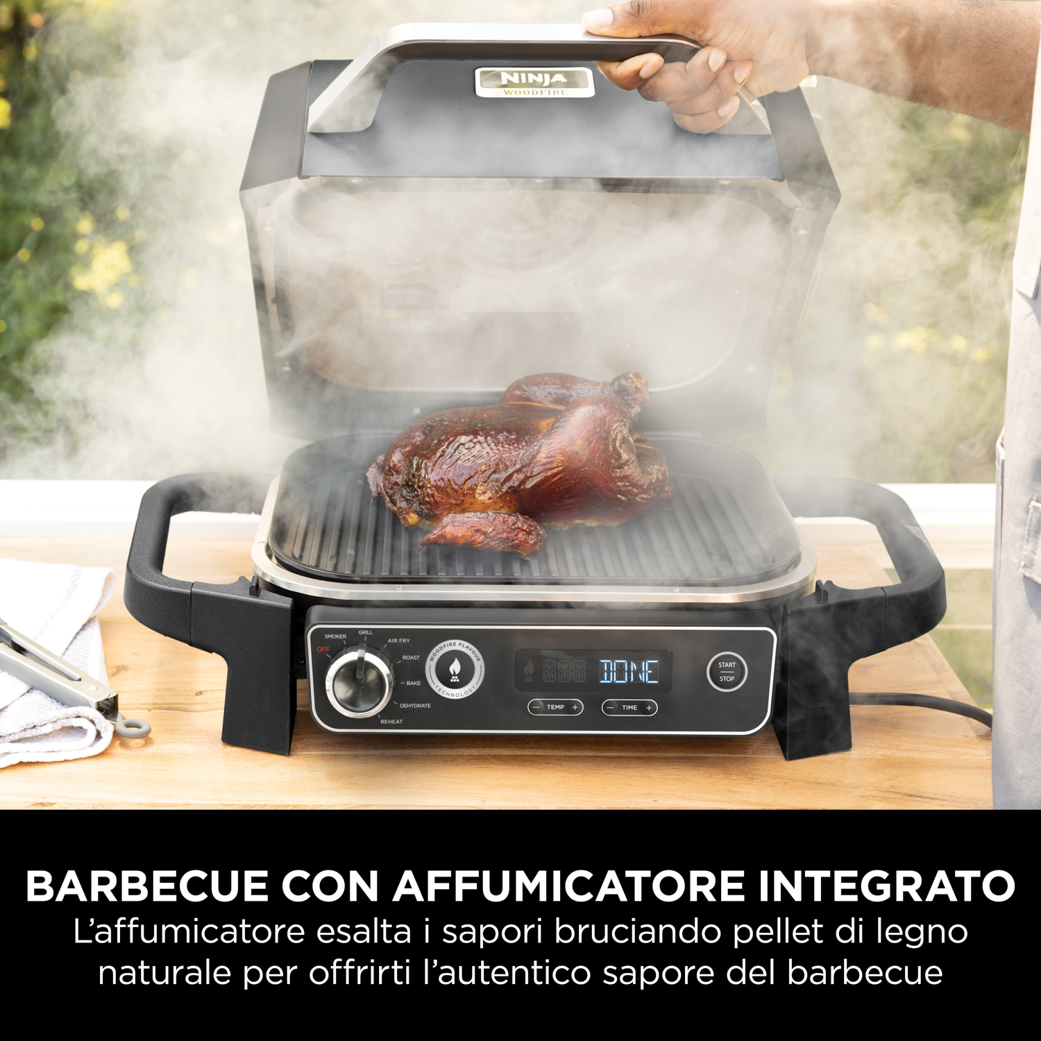Pollo affumicato su una griglia con vapore che sale, azionato da una persona. Testo: BARBECUE CON AFFUMICATORE INTEGRATO.