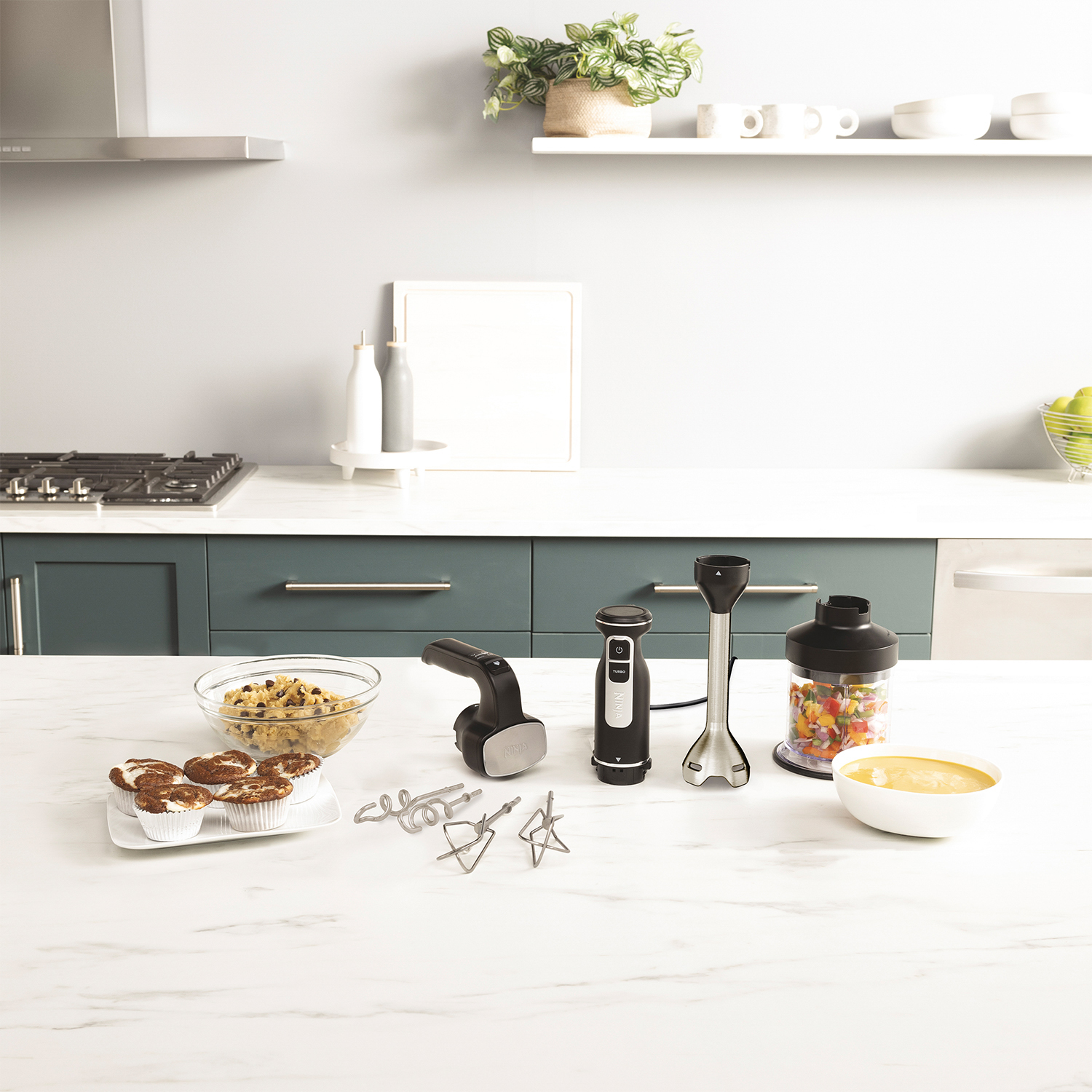 Piano di lavoro della cucina con utensili e ingredienti. Include mixer, frullatore, ciotole e vari accessori.