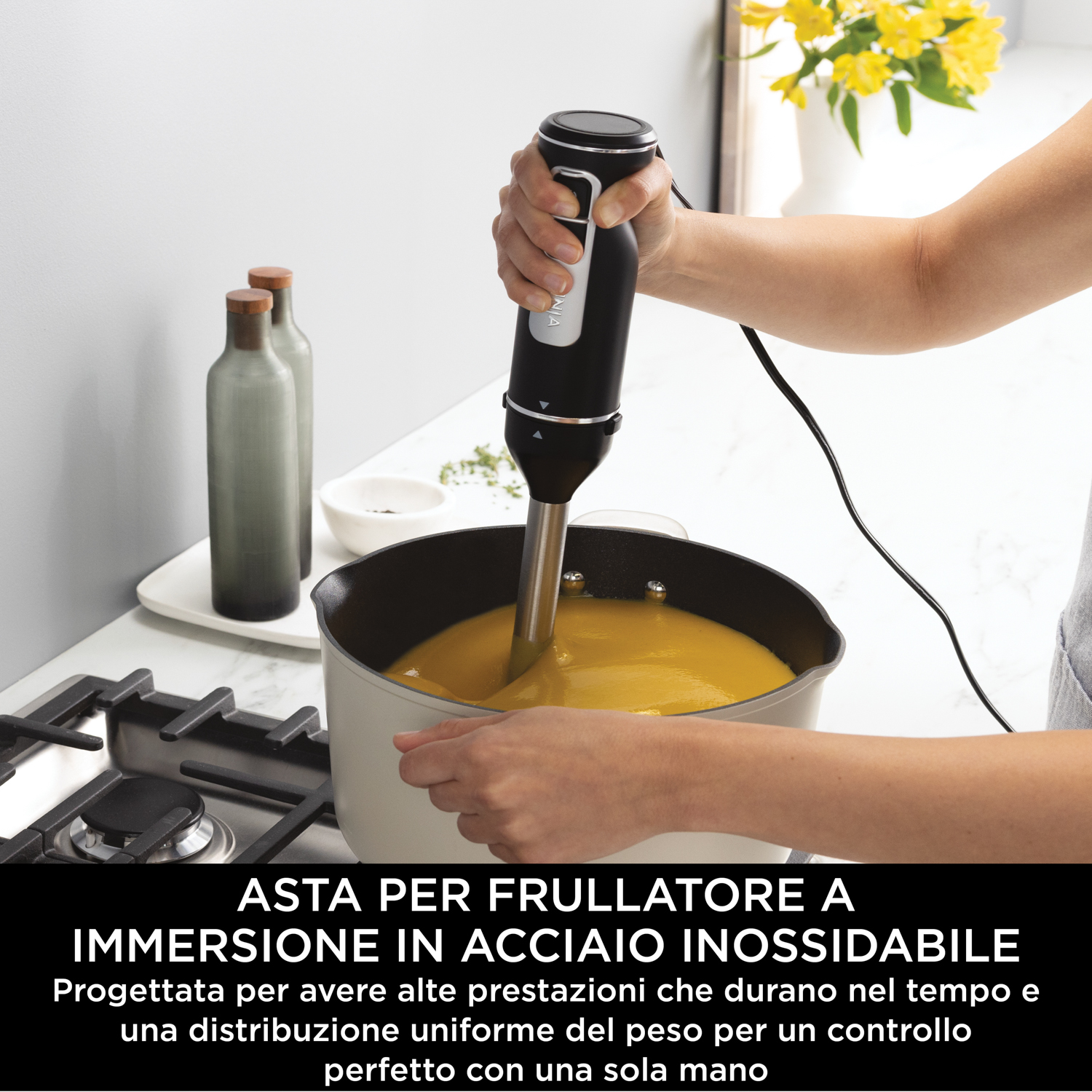 Persona che usa un frullatore a immersione Ninja in una pentola, frullando la zuppa.