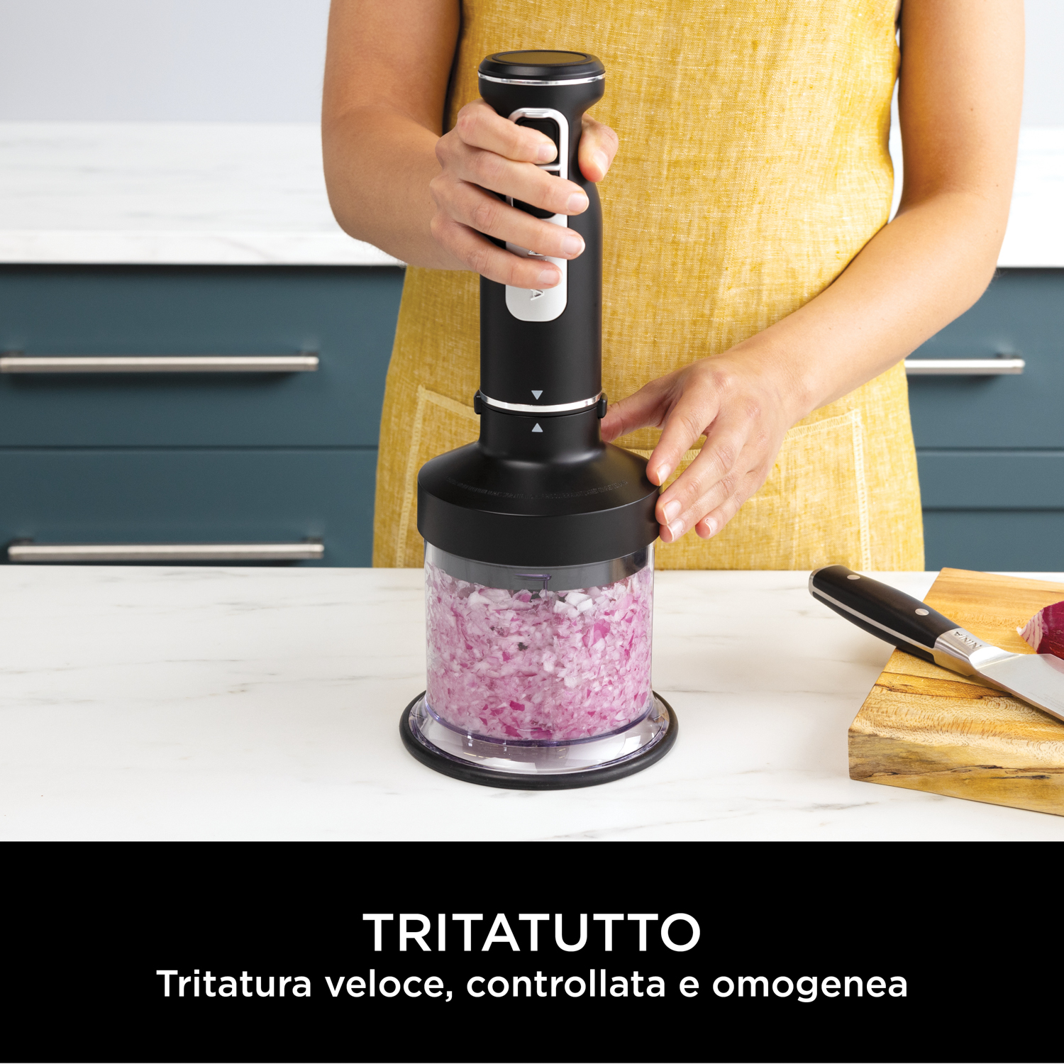 Un tritatutto nero con cipolle rosse tritate all'interno. Una donna lo tiene.