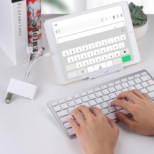 Çok portlu bir adaptöre bağlı bir klavye ve tablet kullanan eller.