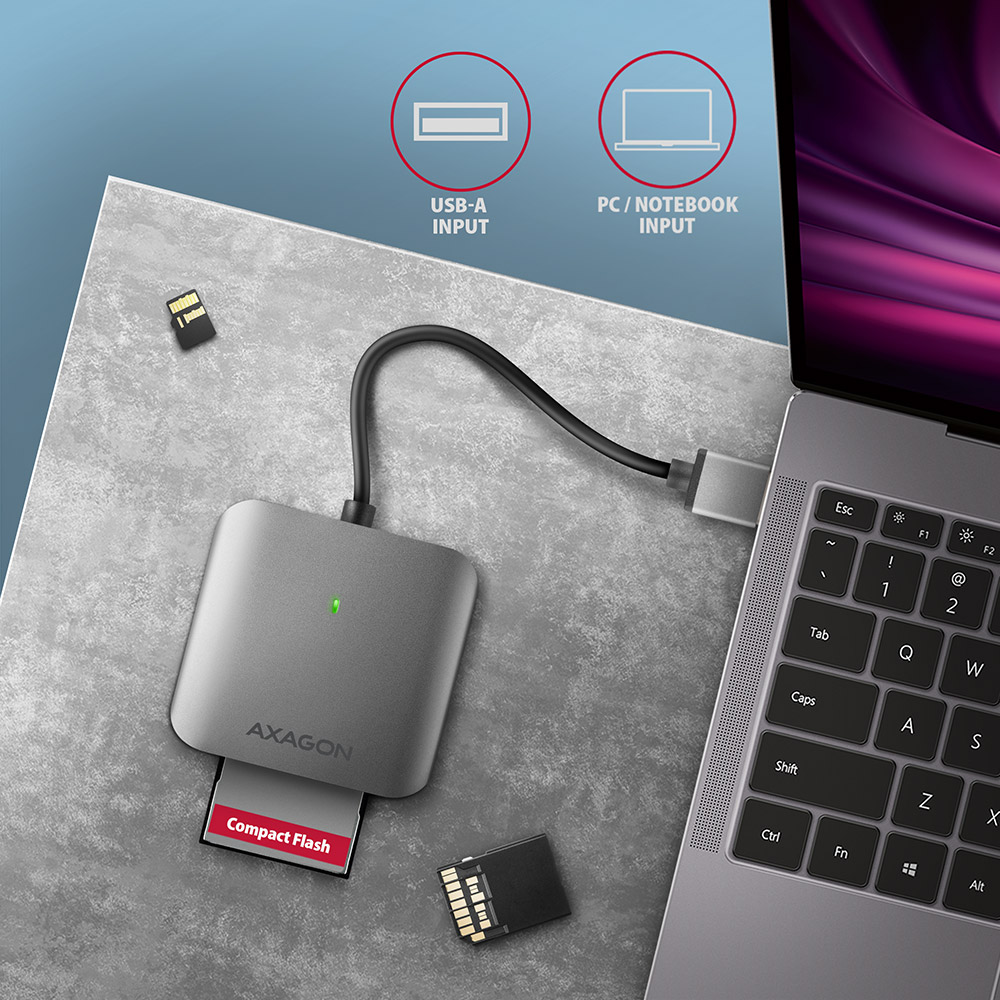 Egy ezüst kártyaolvasó két SD-kártyával és egy laptop a közelben.