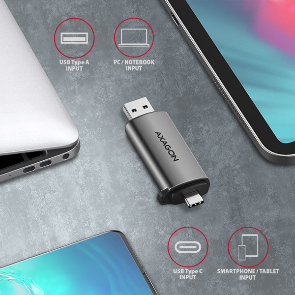 Szürke Axagon USB-adapter USB-A és USB-C bemenetekkel, egy laptop és két okostelefon mellett. A címkék a bemeneti típusokat jelzik.