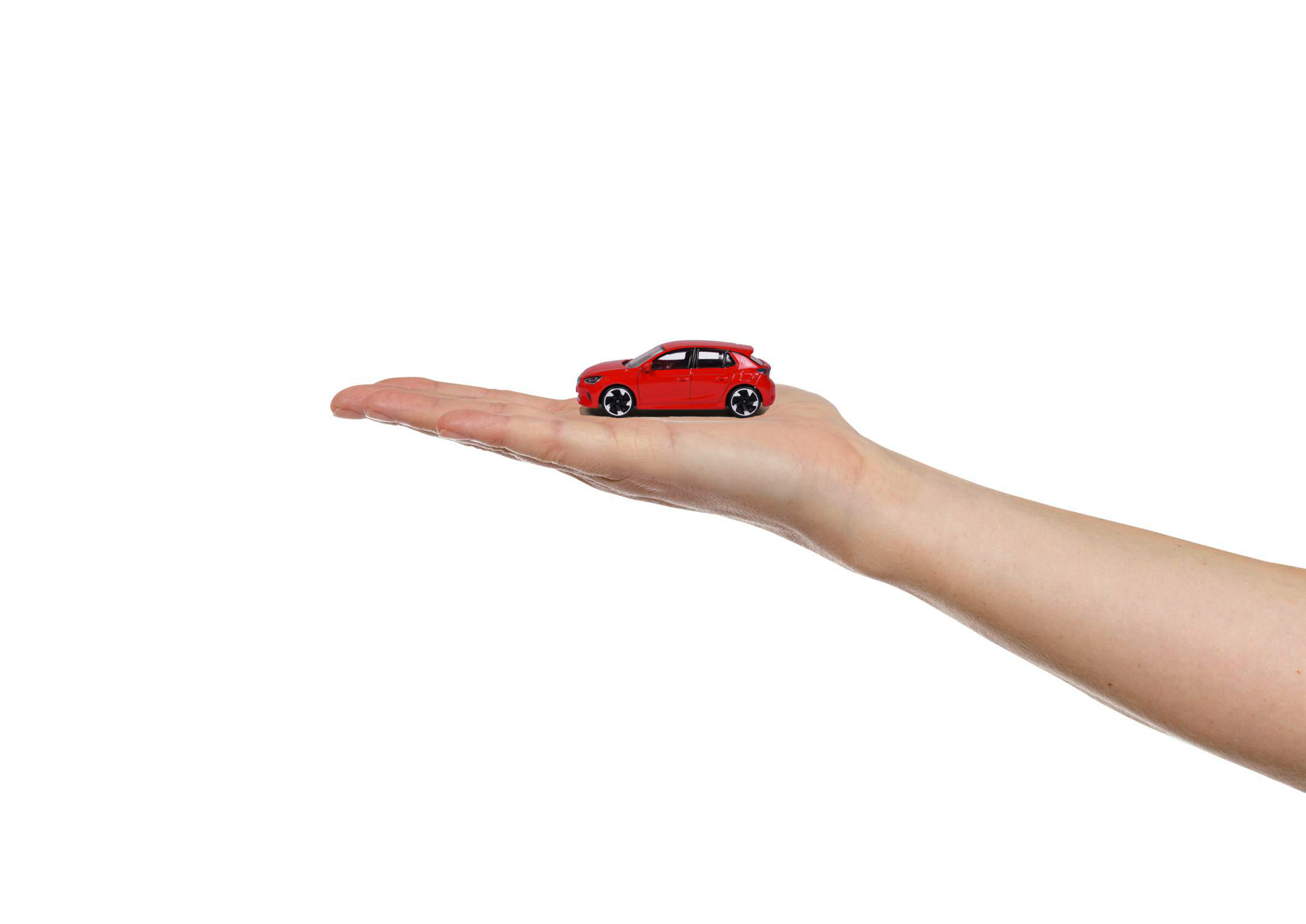 Ein rotes Spielzeugauto wird auf einer offenen Hand vor weißem Hintergrund gehalten.
