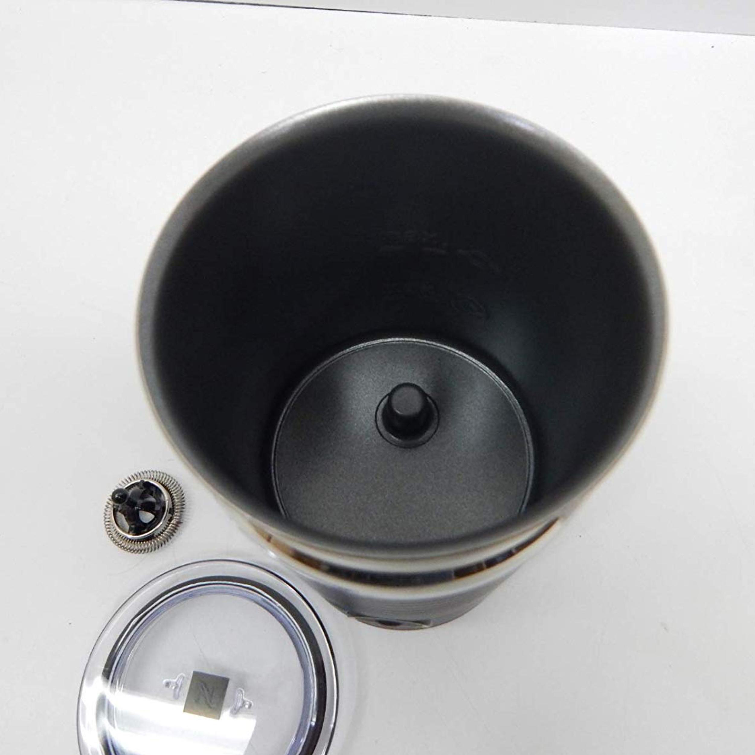 Ein offener, schwarzer Kaffeebereiter-Behälter mit abgenommenem Aufschäumeraufsatz und Deckel.