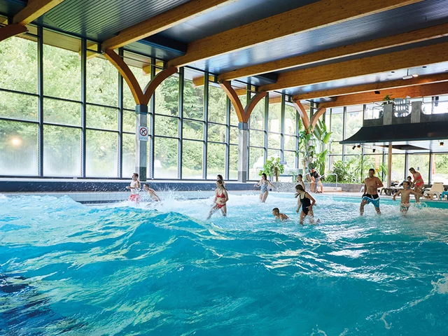 Piscine intérieure avec machine à vagues. Des gens profitent des vagues dans l'eau.