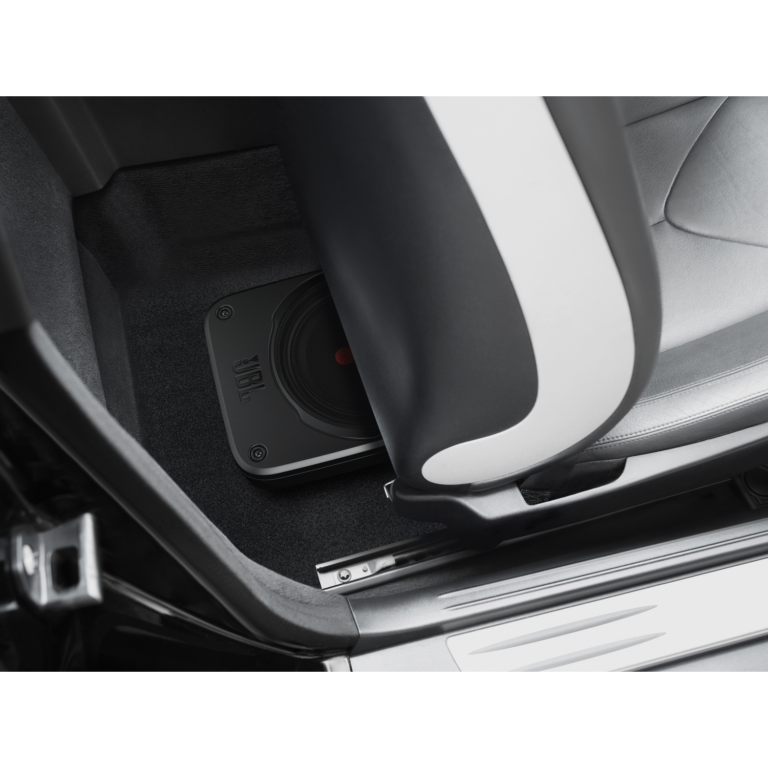 Een JBL subwoofer geïnstalleerd in een auto, onder de stoel.