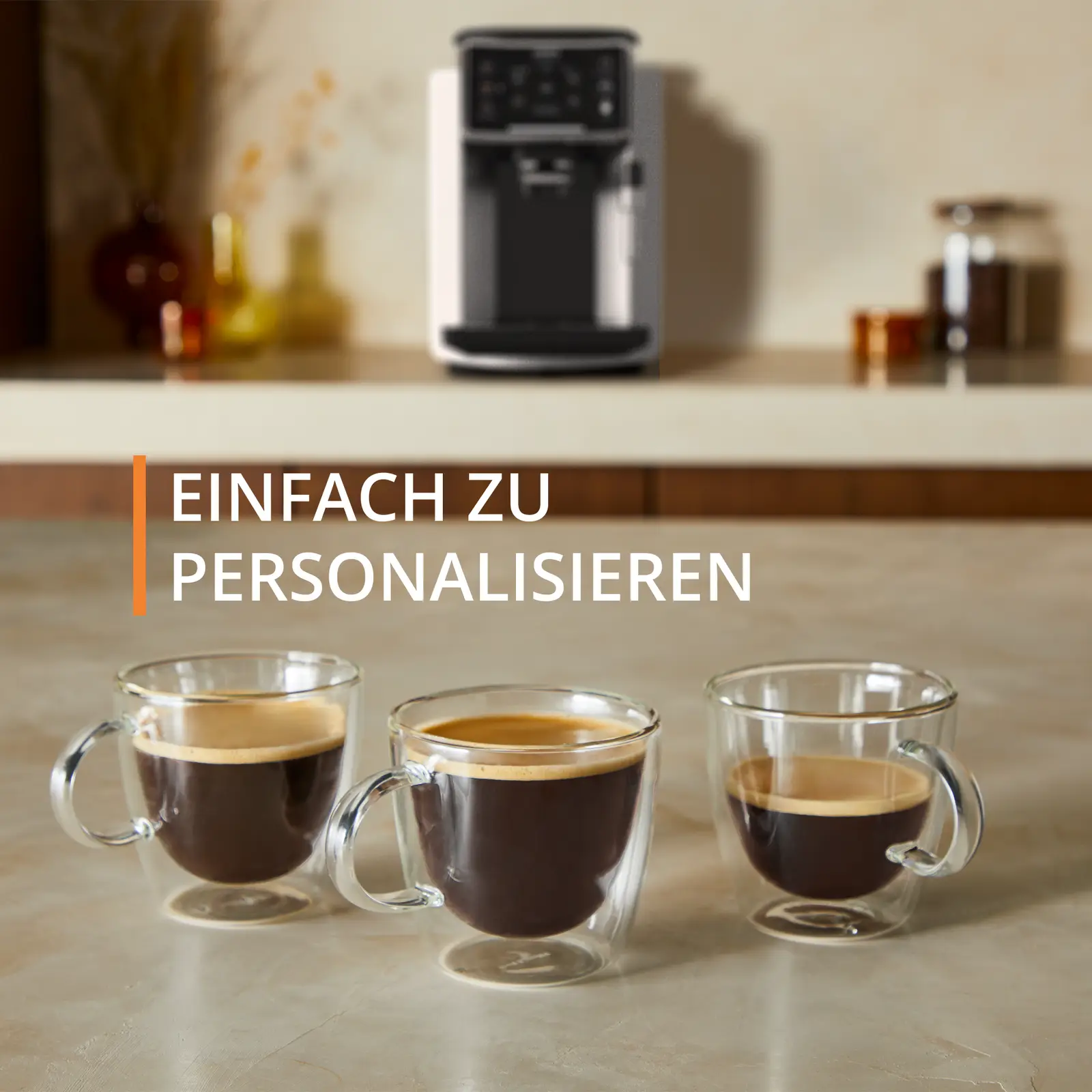 Drei klare Kaffeetassen mit Kaffee, vor einer Kaffeemaschine. Auf Marmor.