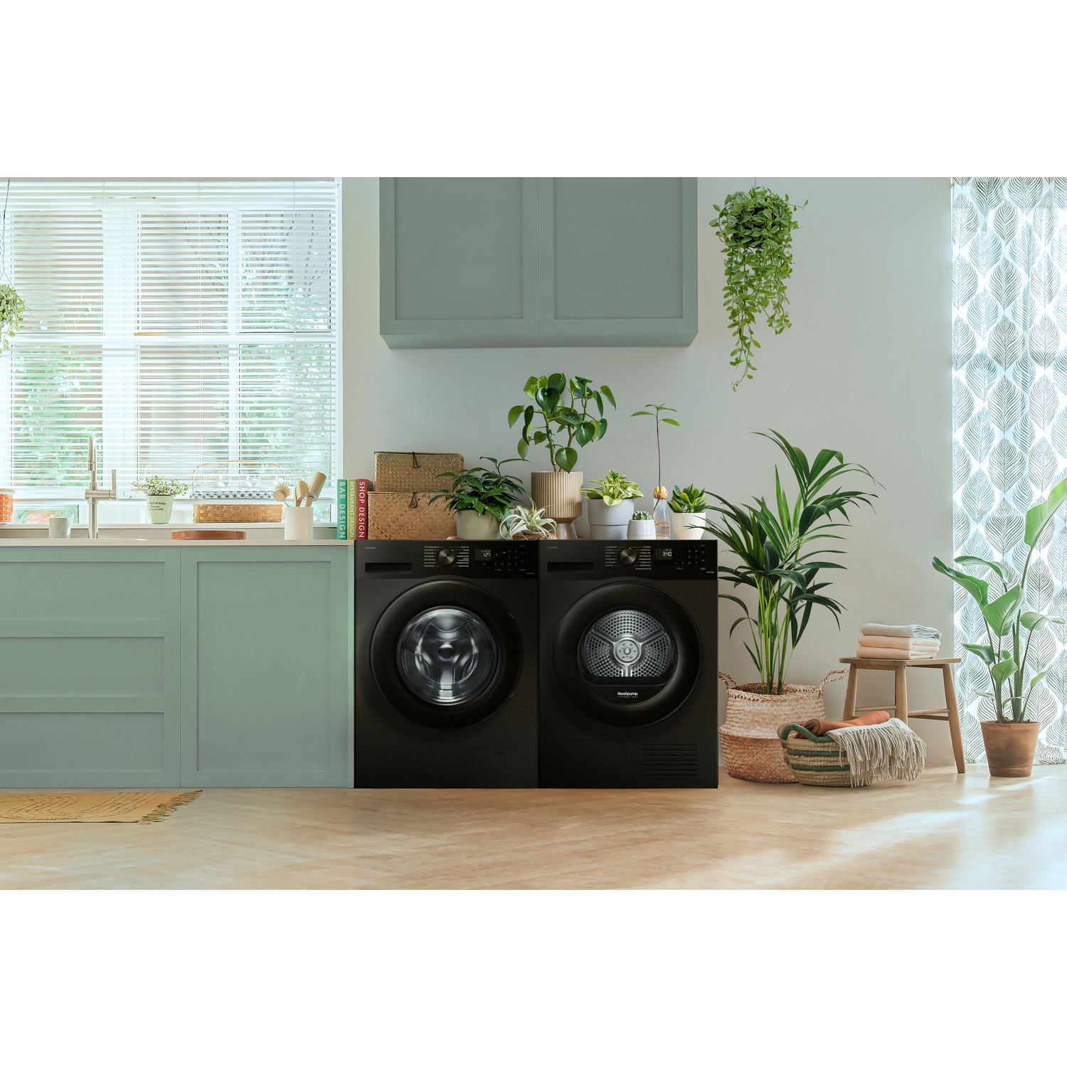 Twee zwarte wasmachines in een keuken. Planten en decoraties dragen bij aan de setting.