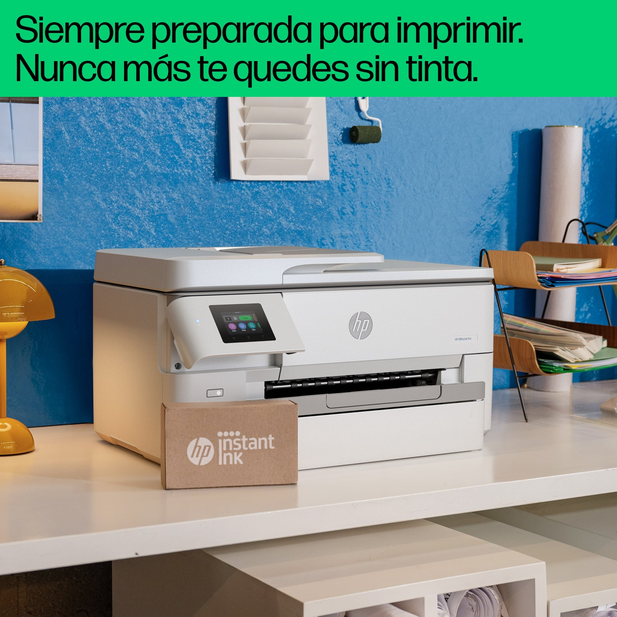 Una impresora blanca con el logotipo de HP, una caja de tinta y una pared azul al fondo.