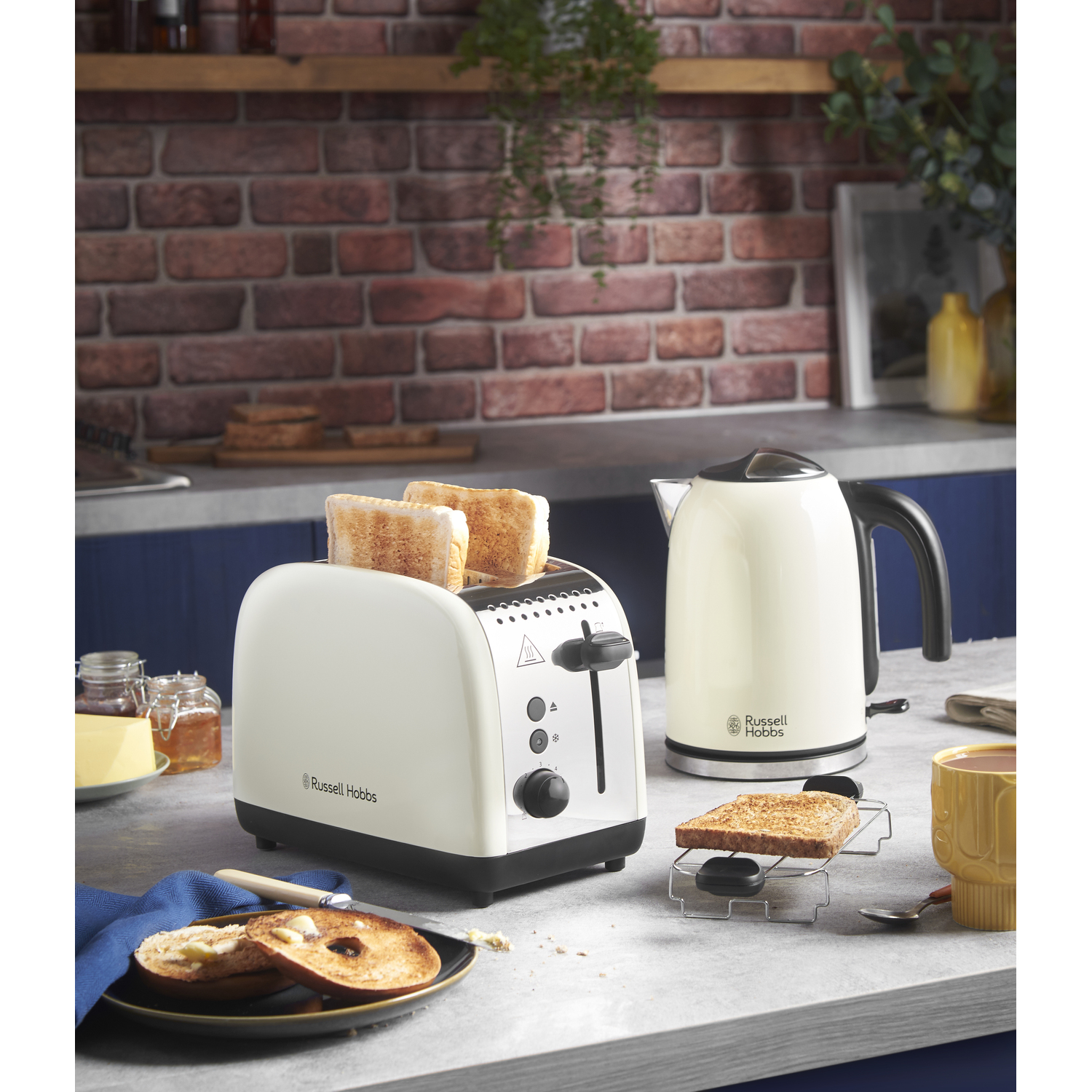 A white toaster with two slices of toast, a white kettle, and other breakfast items on a counter.