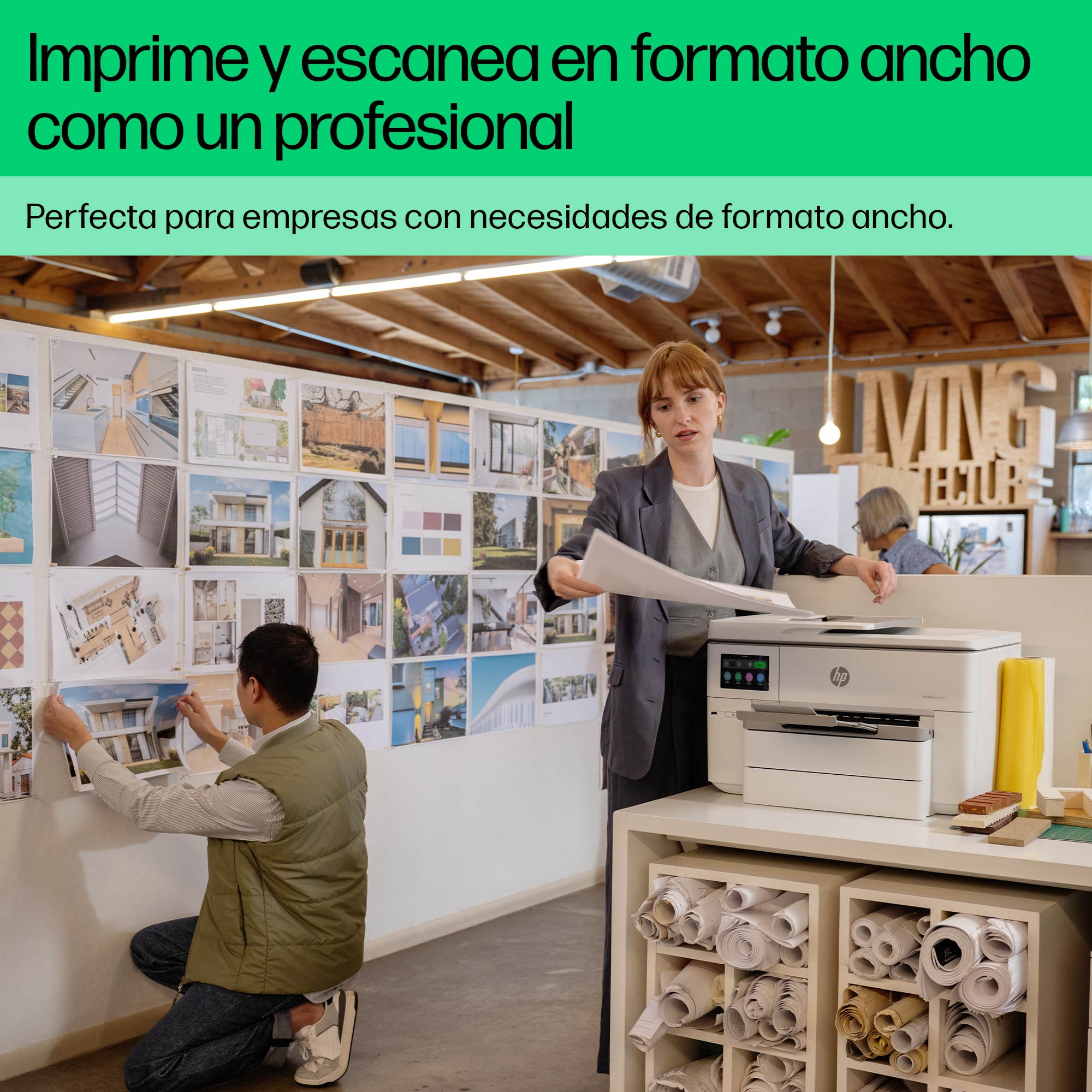 Personas en una oficina usando una impresora y mirando diseños arquitectónicos impresos.