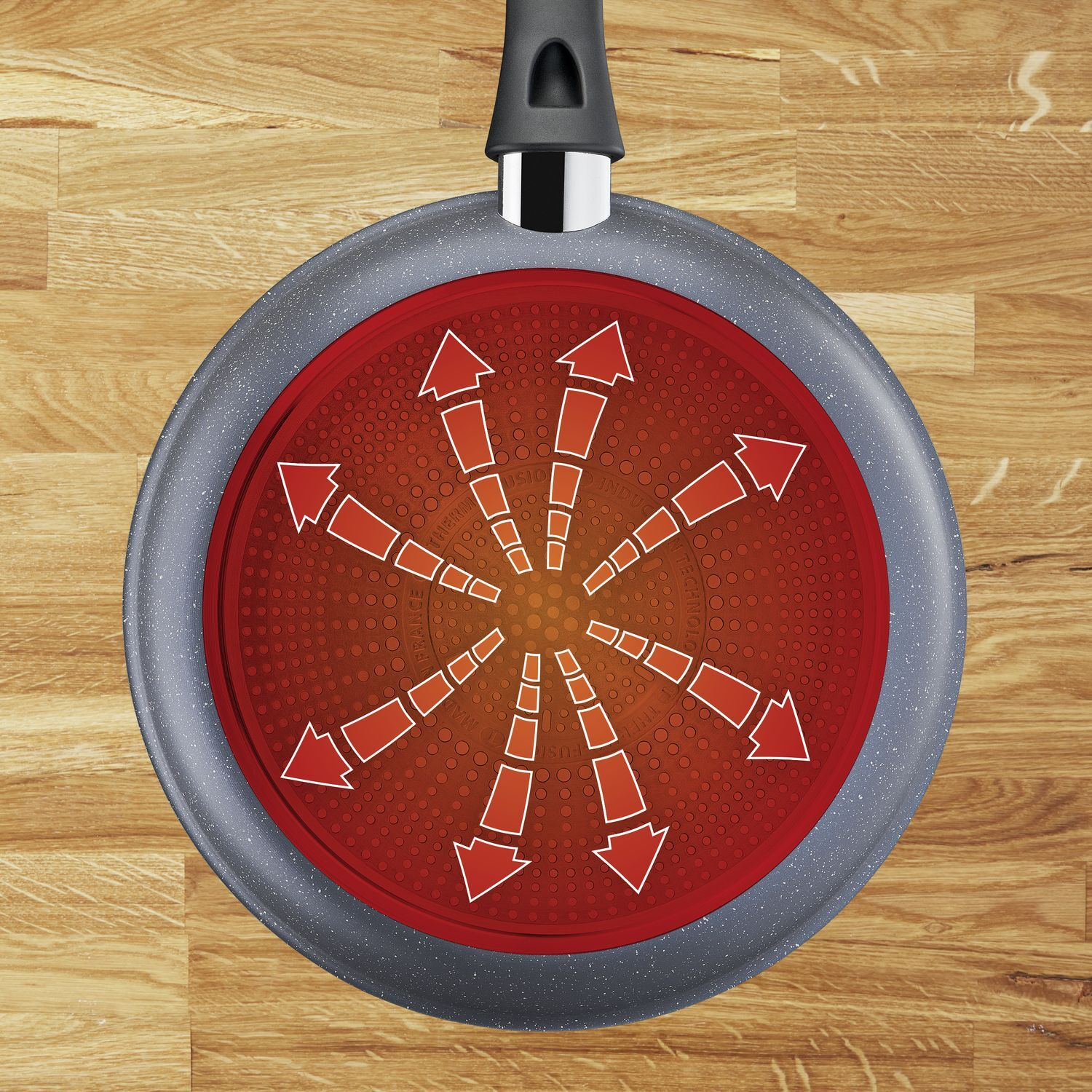 Tefal pan showing arrows indicating heat distribution on a wood surface.