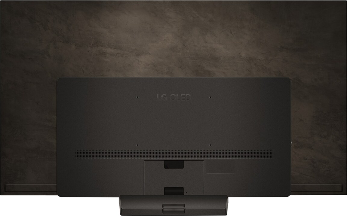 Il retro di una TV nera su una parete marrone scuro. Il televisore ha un supporto in basso.