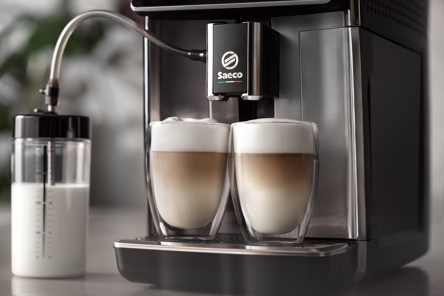 Kaffeemaschine, die zwei Lattes zubereitet. Milchtank links, zwei Kaffeegläser.