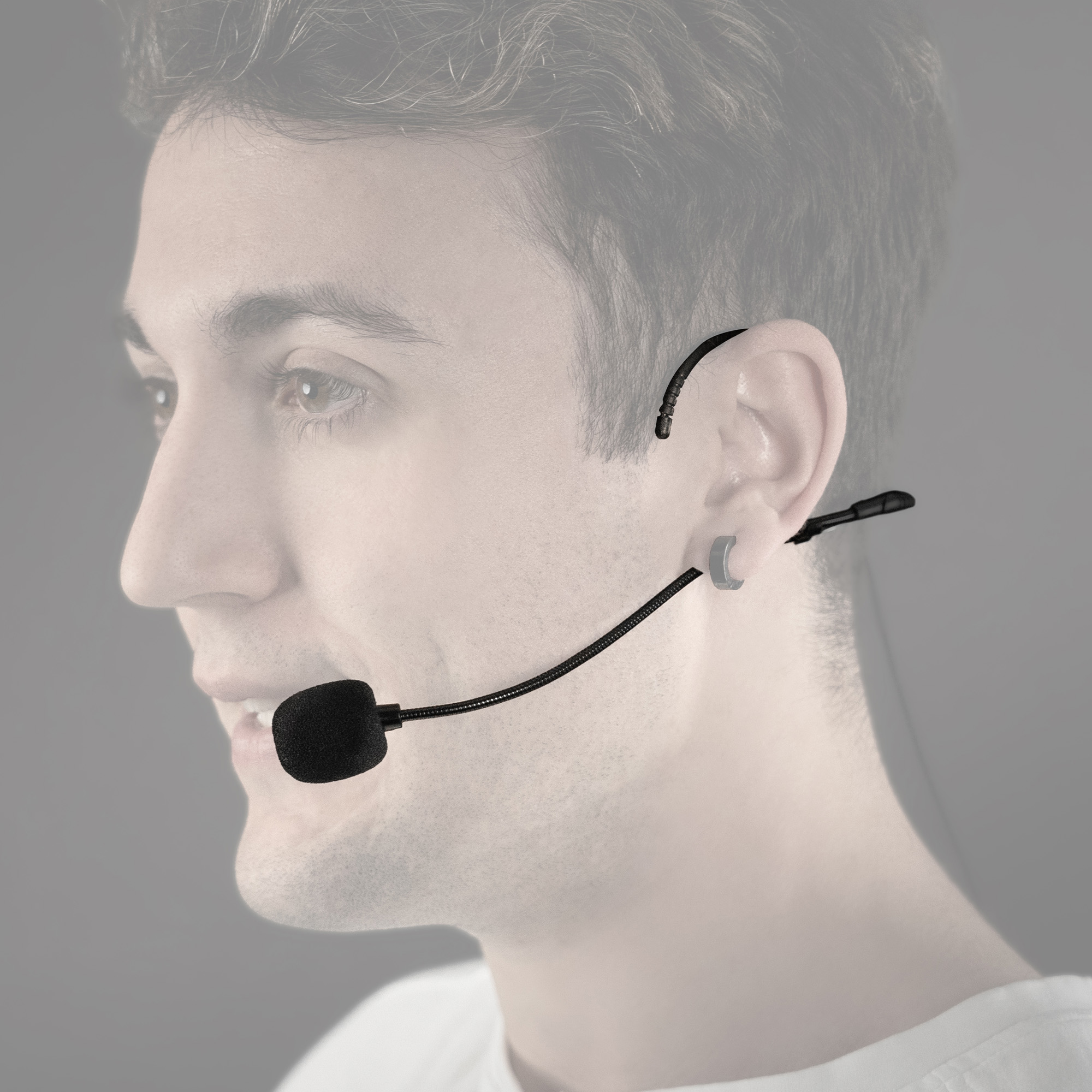 Hombre con micrófono de auriculares, sonriendo, con fondo borroso.