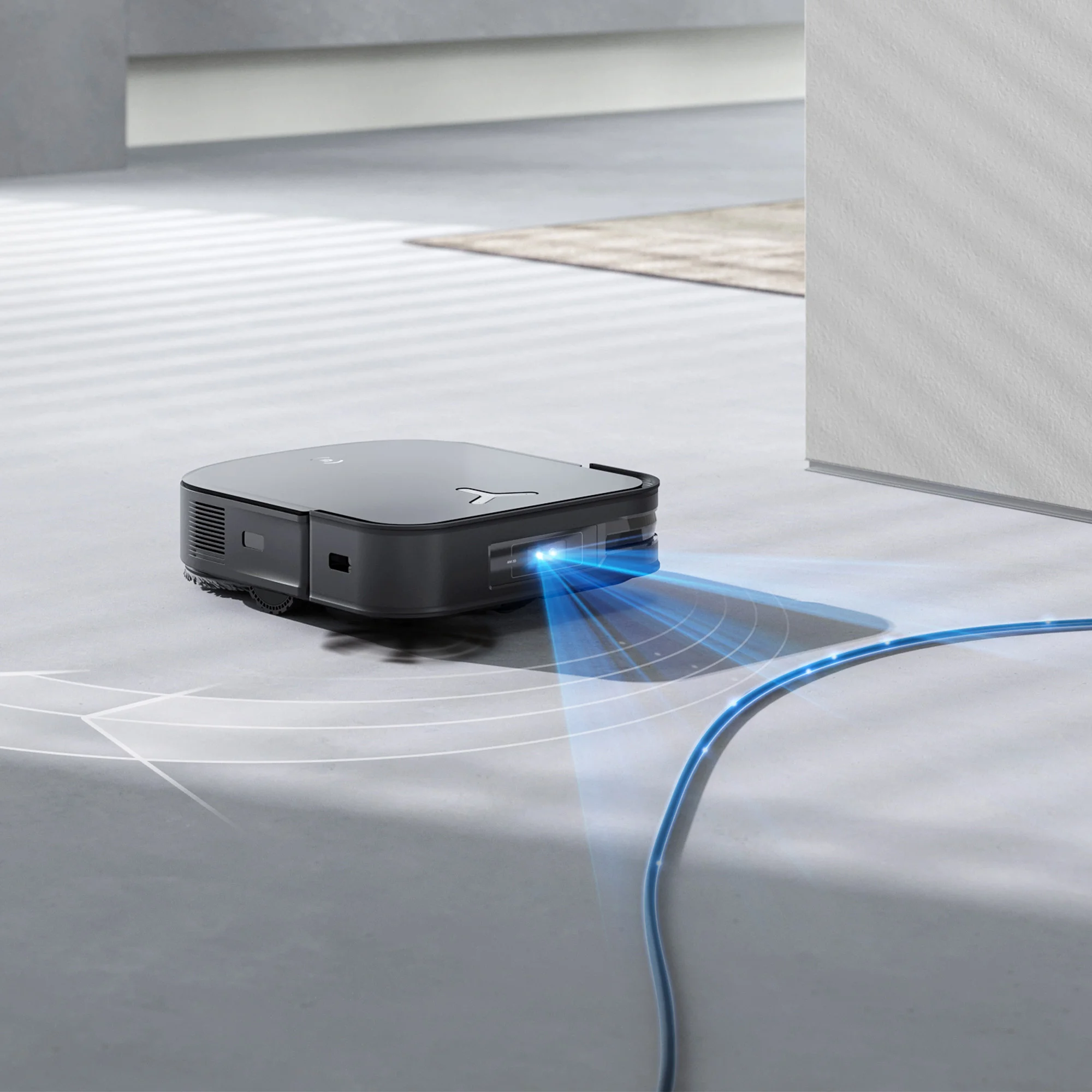 Robot aspirapolvere nero con fascio di luce blu. Si trova su un pavimento chiaro.