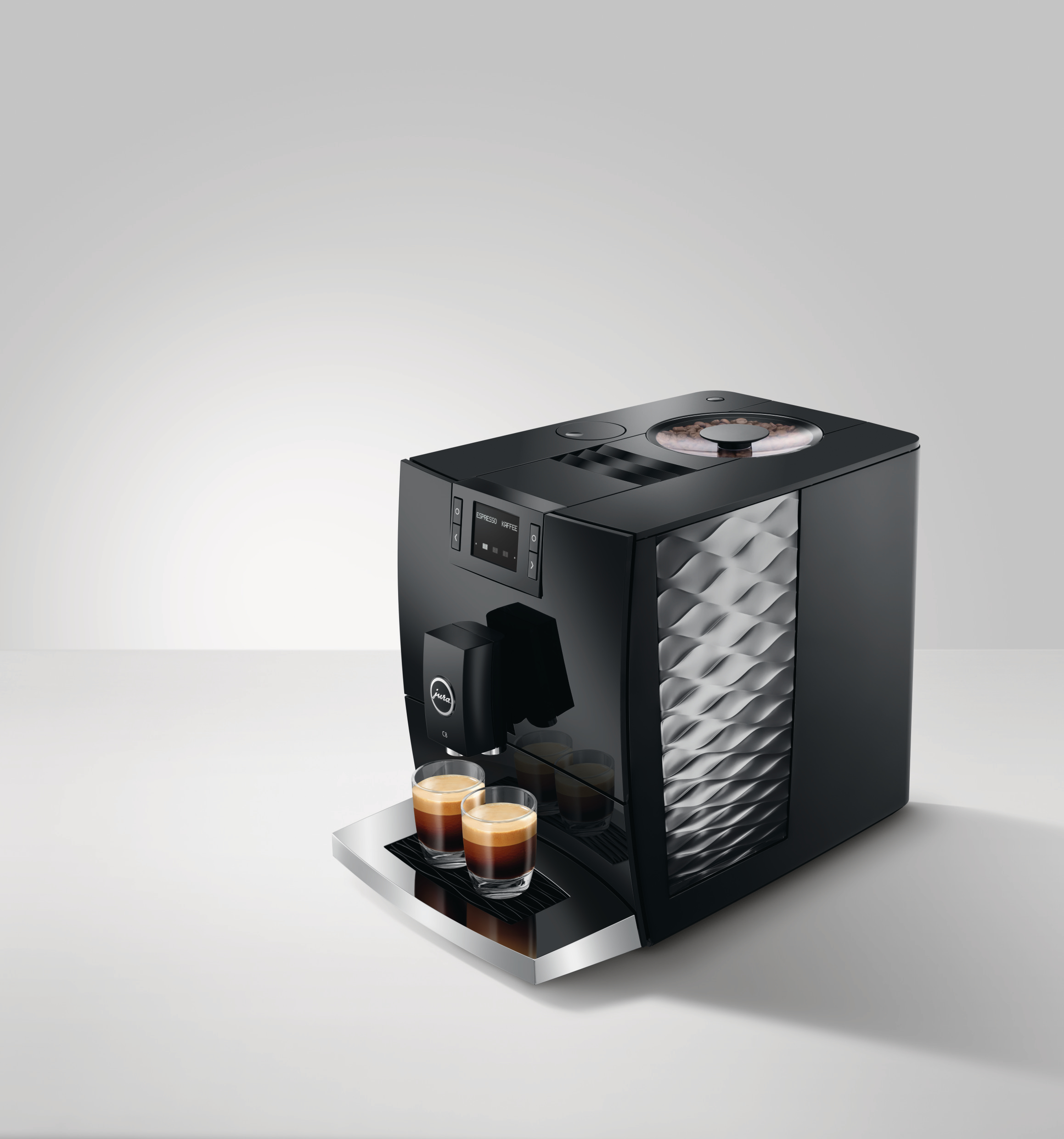 Schwarze Jura Kaffeemaschine mit zwei Espressotassen auf einer weißen Theke.