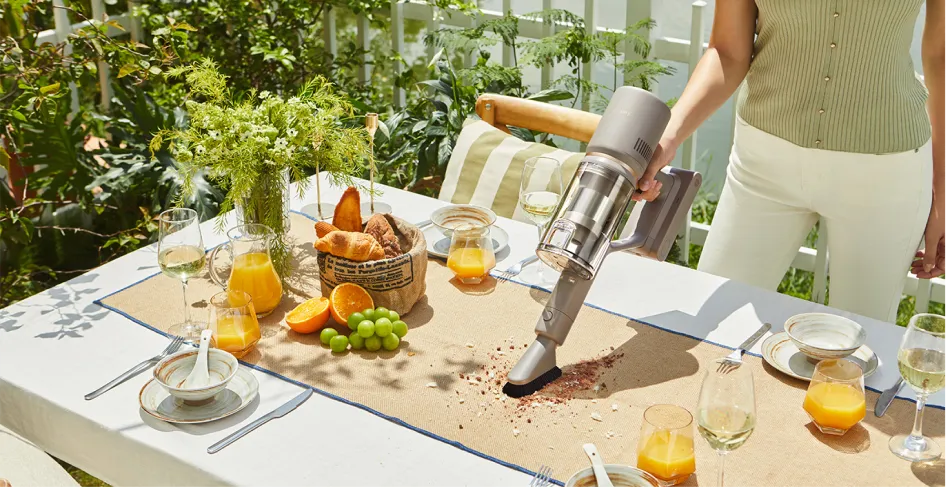 Un aspirateur à main nettoie une table extérieure garnie de nourriture.
