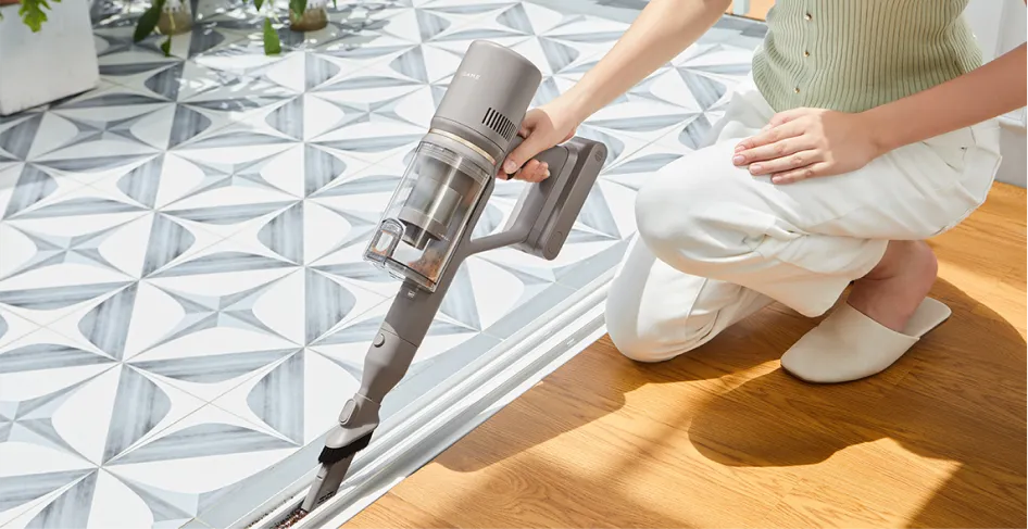 Une personne passe l'aspirateur dans un espace étroit avec un aspirateur à main gris.