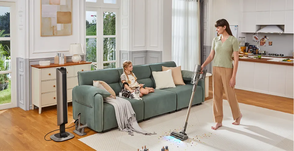 Une femme passe l'aspirateur dans un salon avec une fille, un chat, un canapé et un meuble.
