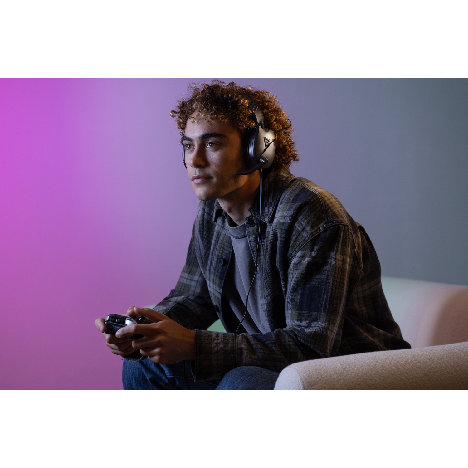 Man wearing headphones, playing a game with a controller. Colorful background.