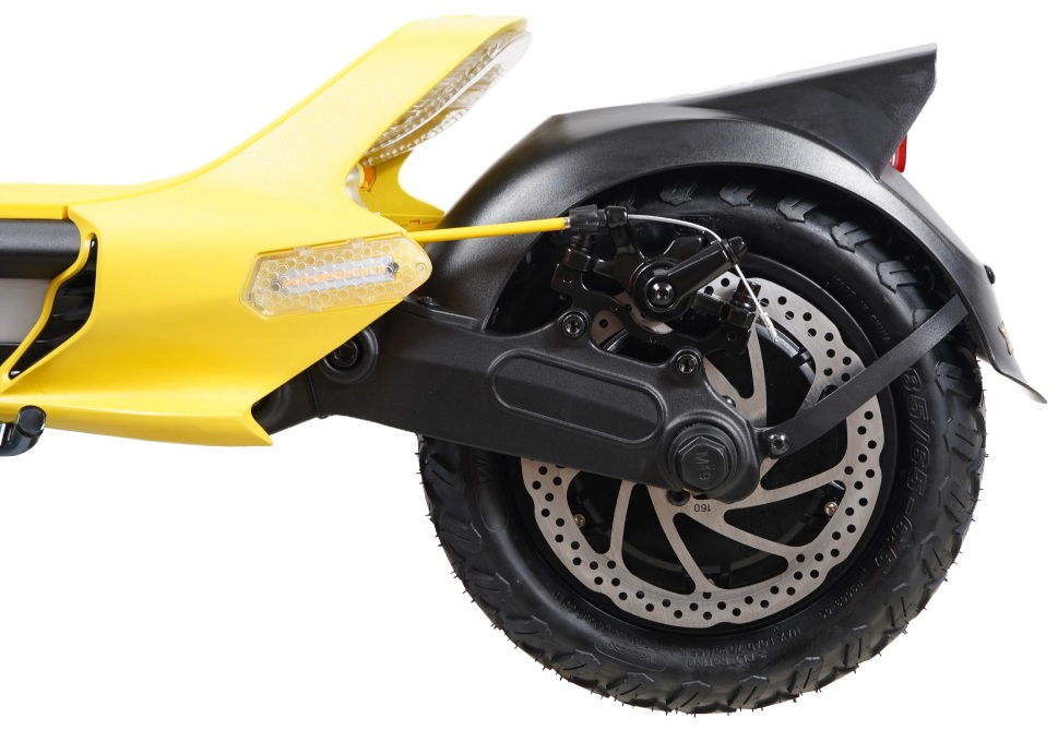 Tylne koło żółtej hulajnogi, czarny błotnik, hamulec tarczowy i opona, na białym tle.