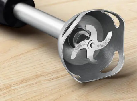 Zbliżenie srebrnego ostrza blendera na drewnianej powierzchni.