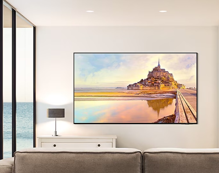 Telewizor na ścianie z malowniczym widokiem. Stół i lampa znajdują się przed ścianą.