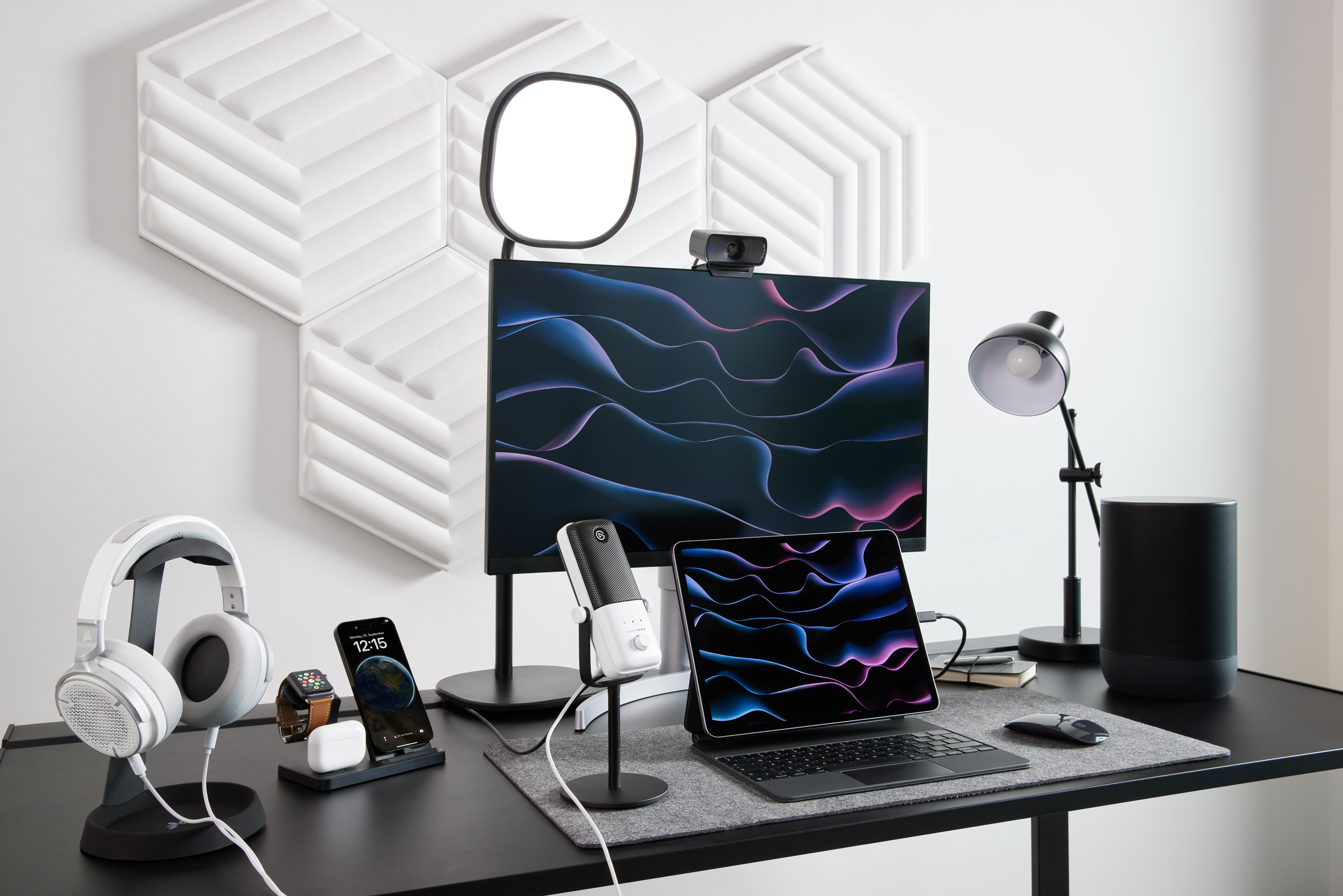 Schreibtisch mit Monitor, Kopfhörern und Zubehör. Weißer Hintergrund.