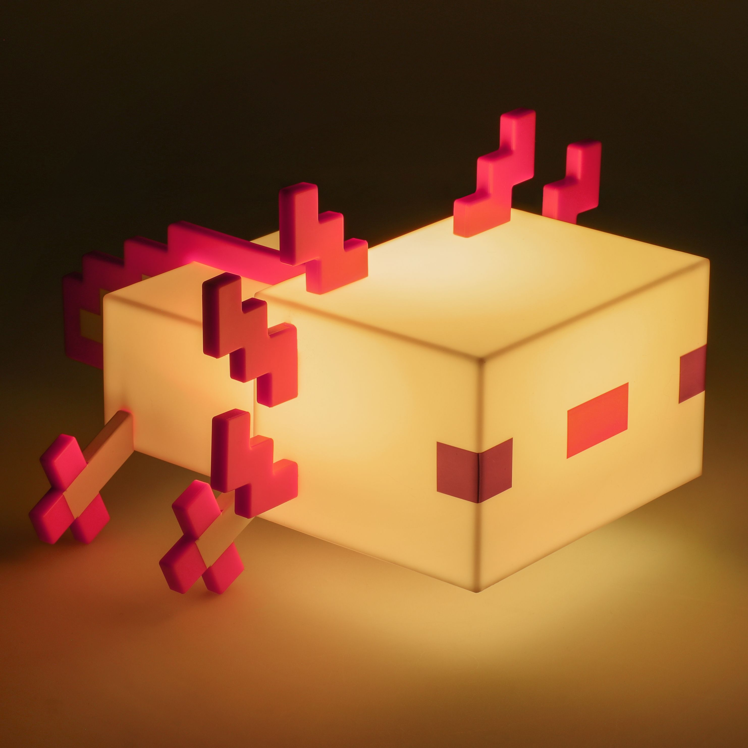 Eine Minecraft-Axolotl-Lampe leuchtet gelb mit rosa Akzenten, vor dunklem Hintergrund.