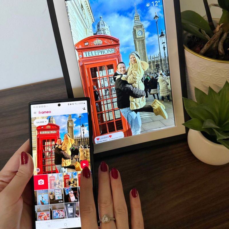 Egy okostelefon egy londoni fotót jelenít meg egy digitális képkeret mellett.