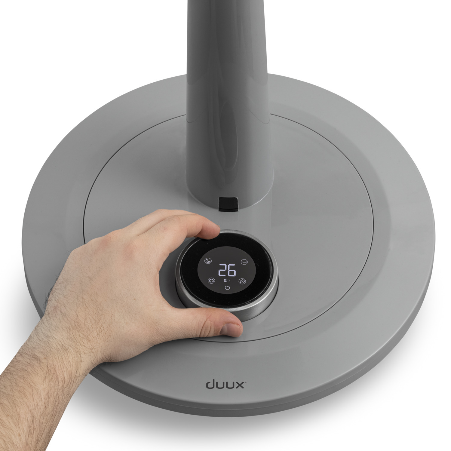 Hand draait een draaiknop op de grijze voet van een ventilator. Display toont temperatuur.