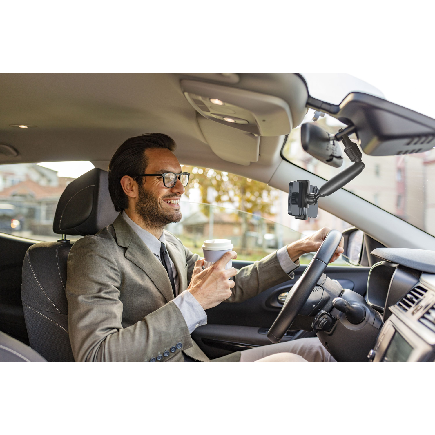 Man in een auto, met een koffie en een telefoonhouder.