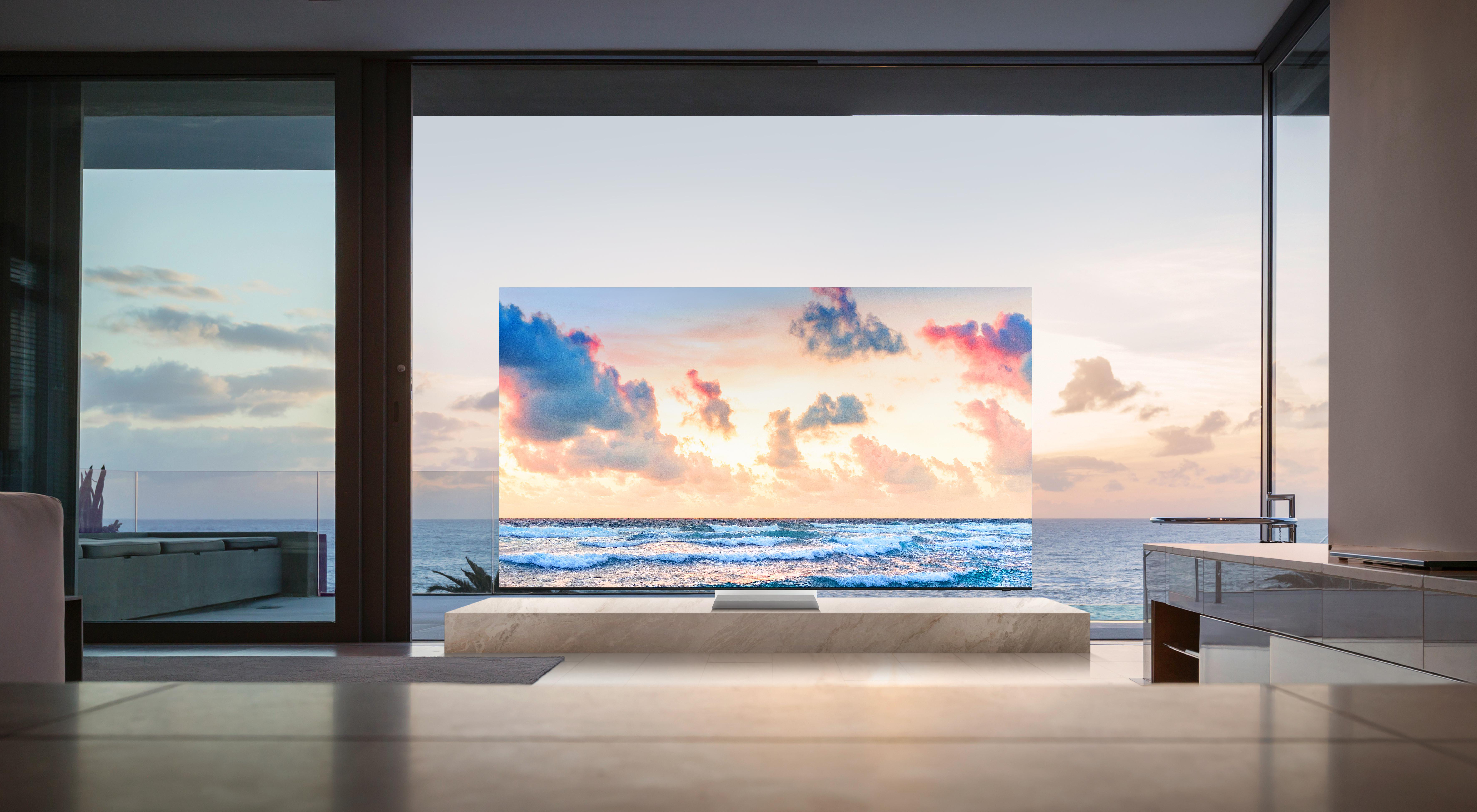 Ein großer Fernseher zeigt eine Strandszene über dem Meer. Der Fernseher steht in einem Wohnzimmer.