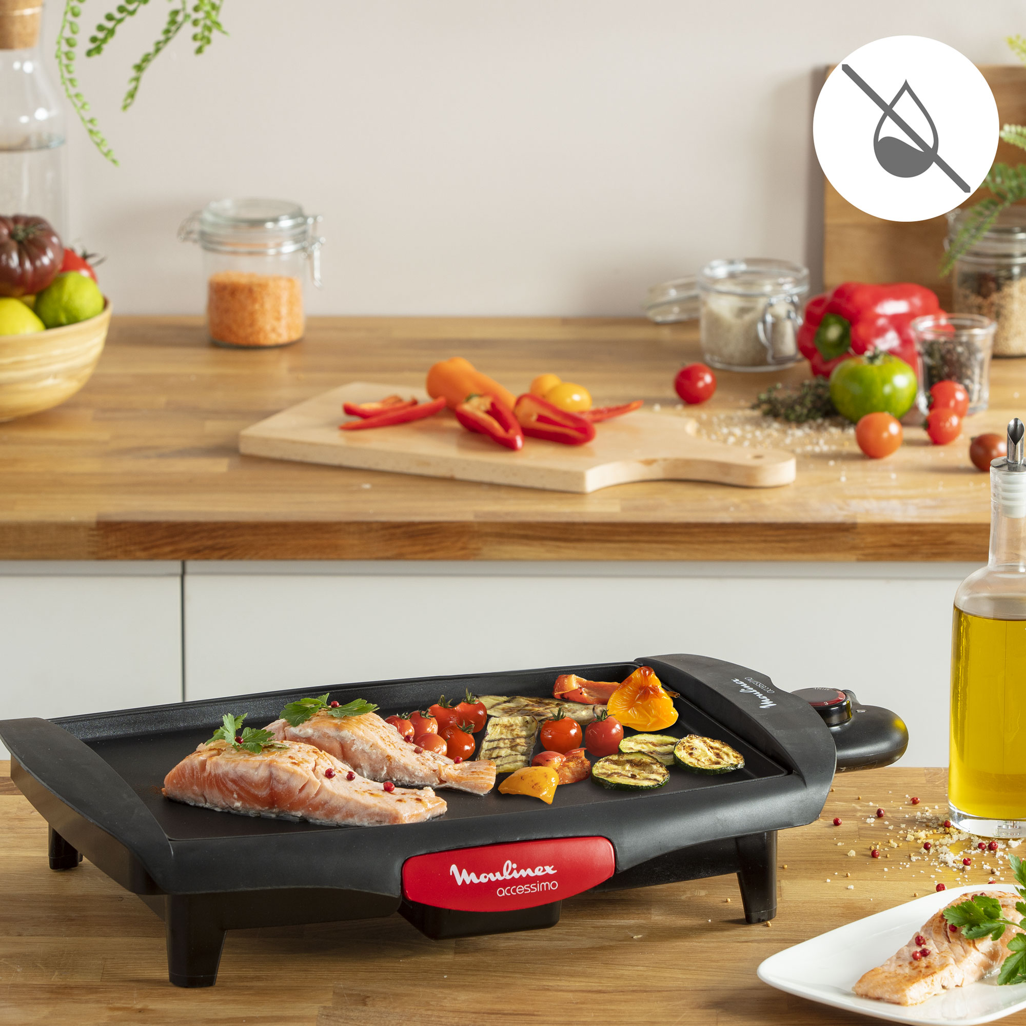 Parrilla eléctrica con salmón, verduras y botella de aceite sobre una superficie de madera.