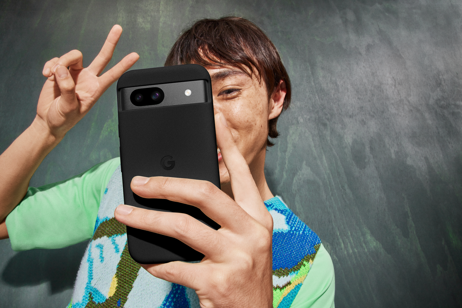 Una persona tomando un selfie con una funda negra, haciendo el signo de la paz.