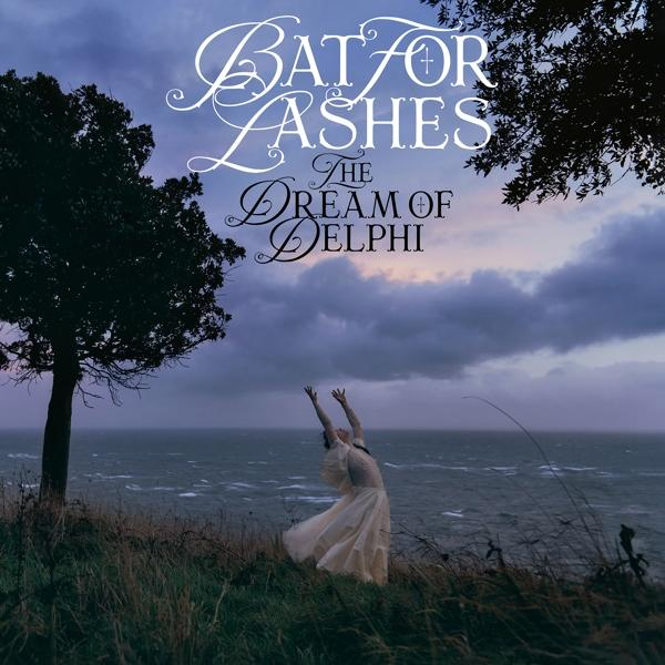 A 'Bat for Lashes - The Dream of Delphi' album borítója, karjait felemelő nő, tenger és felhős égbolt a háttérben.