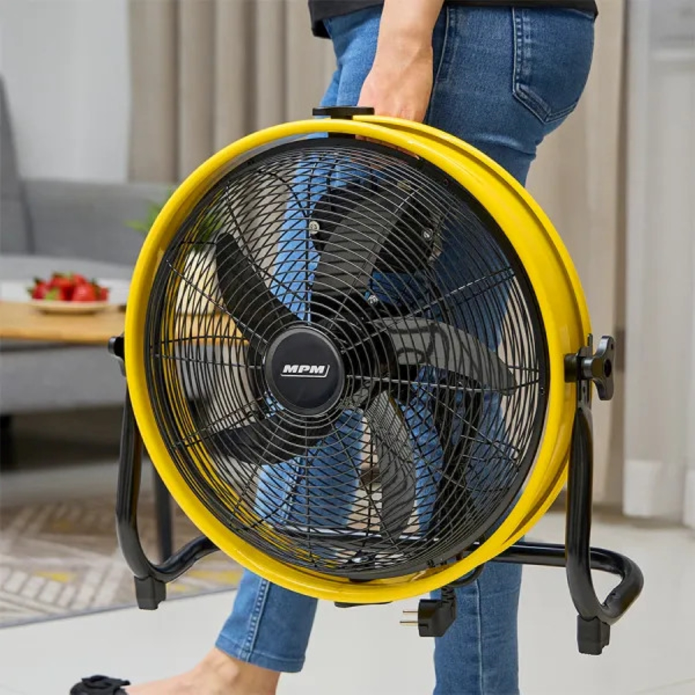 Osoba trzymająca żółty wentylator w pokoju.