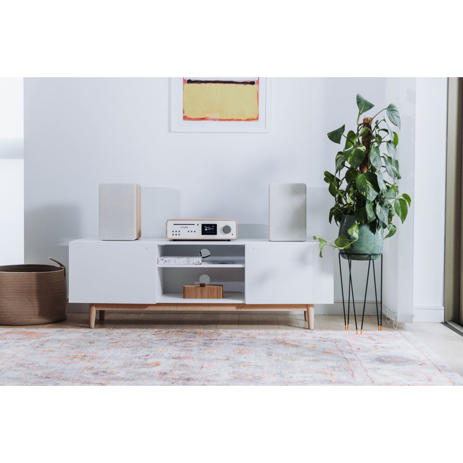 Living room with white furniture, a radio, and a plant. A rug is on the floor.