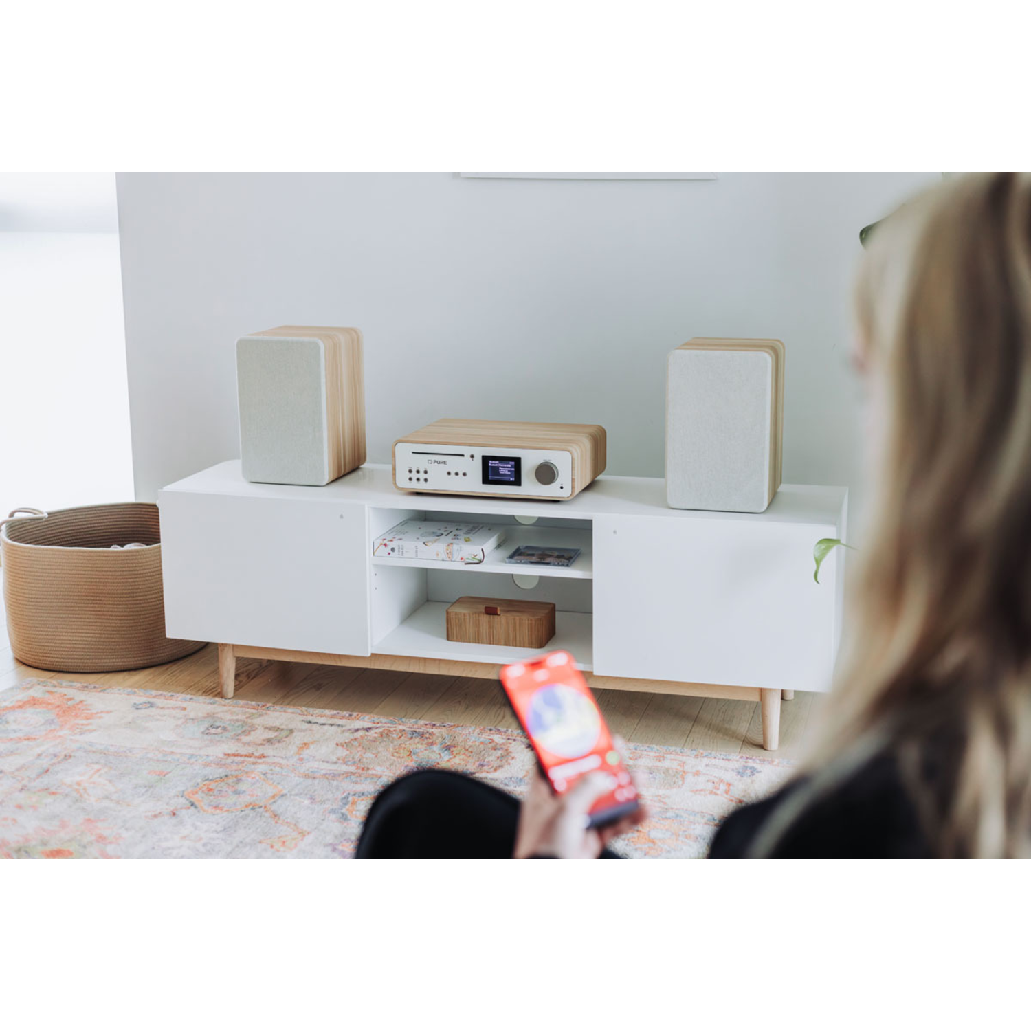 Living room with speakers, a stereo, and a person holding a phone.