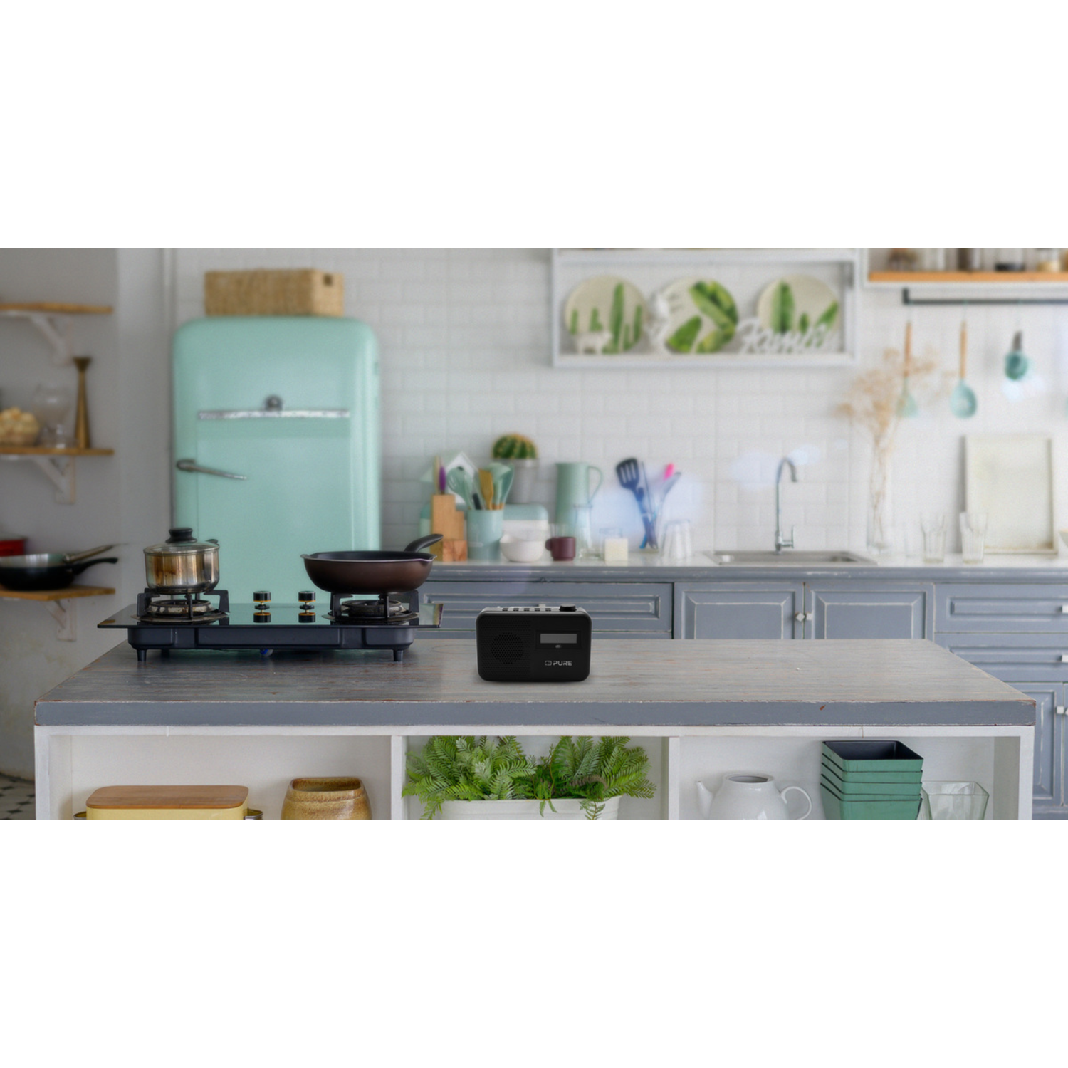 A kitchen counter with a stove and frying pan on top. A small radio sits on the counter.