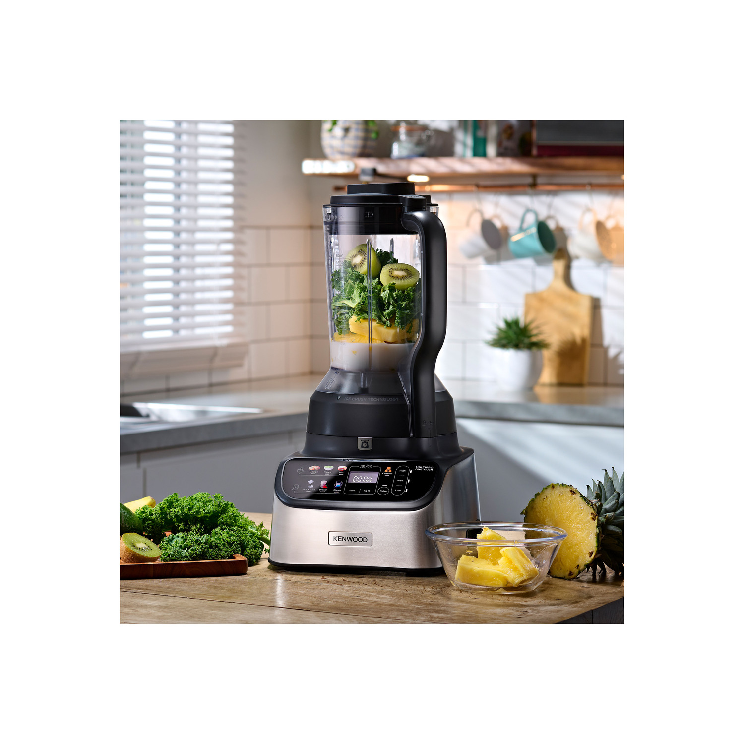 A silver and black blender with ingredients inside and cut fruits and vegetables around it.