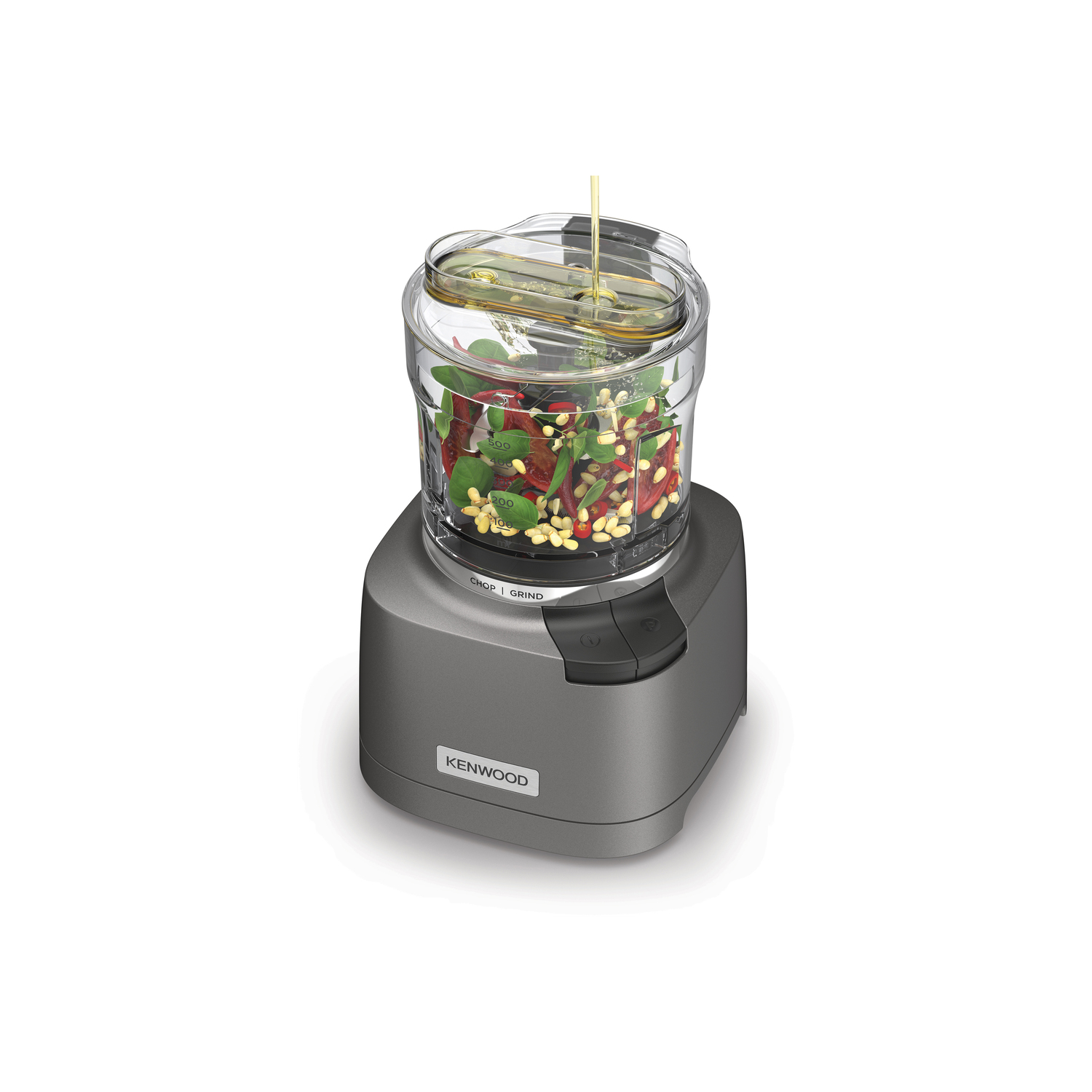 Keukenmachine met doorzichtige container met ingrediënten, olie wordt van bovenaf ingegoten.